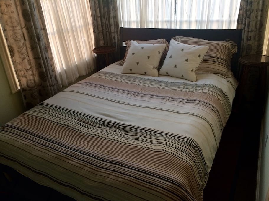 Queen-size bed adjacent to living room suite with beautiful natural light.