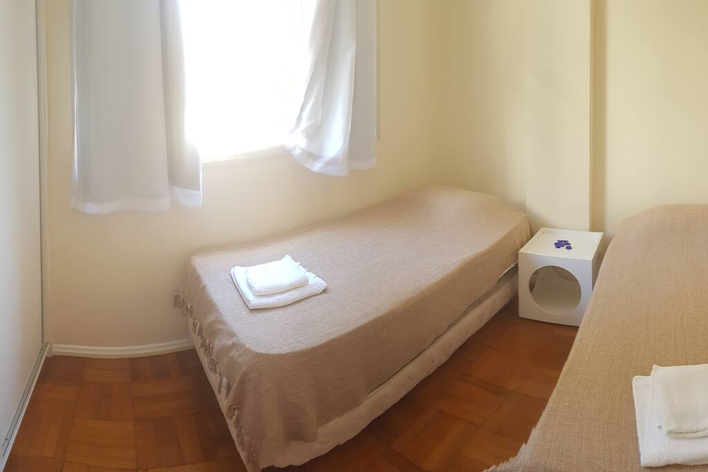 Quarto de solteiro com duas camas de solteiro e duas camas auxiliares, armário amplo e ventilador de teto.