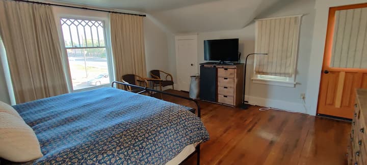 חדר שינה גדול בקומה השנייה עם טלוויזיה וגישה למרפסת.