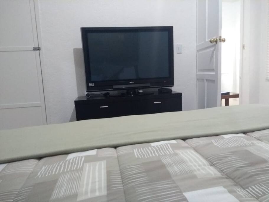 La habitación es amplia y muy iluminada. Cuenta con un closet grande para almacenar maletas y colgar tu ropa. Además de una cajonera si necesitas más espacio de para guardar tus cosas. Y sobre la cajonera una gran pantalla HD para ver tus series preferidas.