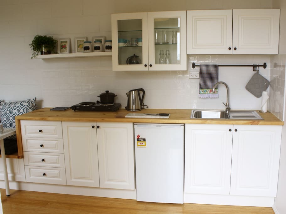 Open plan kitchen, including tea, coffee, a hotplate with pots and pans.