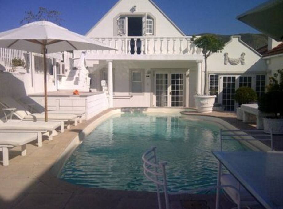 Sparkling sunny pool area with chaizes, umbrellas and towels