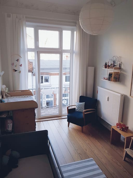 Kinderzimmer mit Wickelkommode und Zugang zum Balkon Richtung Innenhof