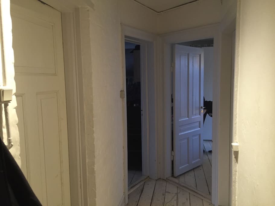 The hallway. To the right is the kitchen. Next door right is bathroom. The one at the end to the right is a room with double bed and space for clothes. Down to the left is the living room. To the very left is another room with double bed.