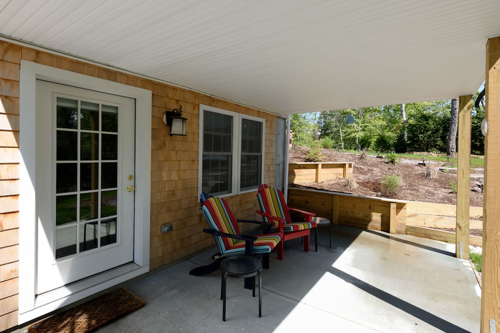 Bright and airy patio with Adirondack cushioned chairs, gas grill and outdoor shower