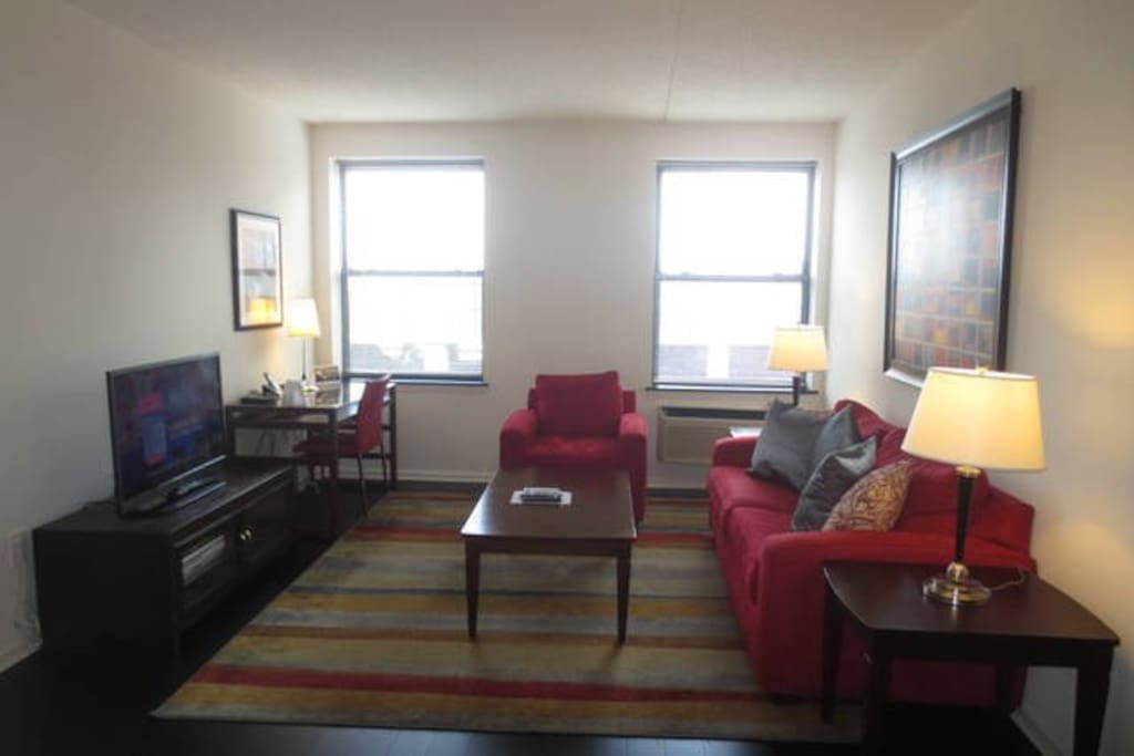 Spacious living room with entertainment center and convenient work desk with chair, lamp and WiFi
