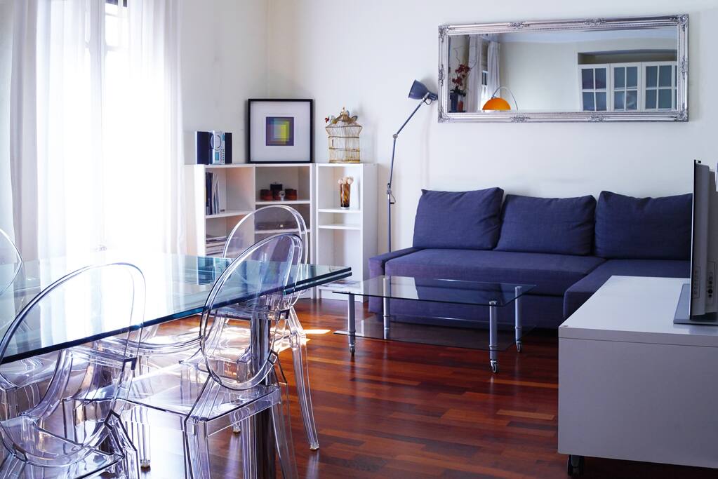 Main living room with TV, dinning table, comfy sofa and two cosy balconies facing a quite street in front of 5* Hotel Fuster
