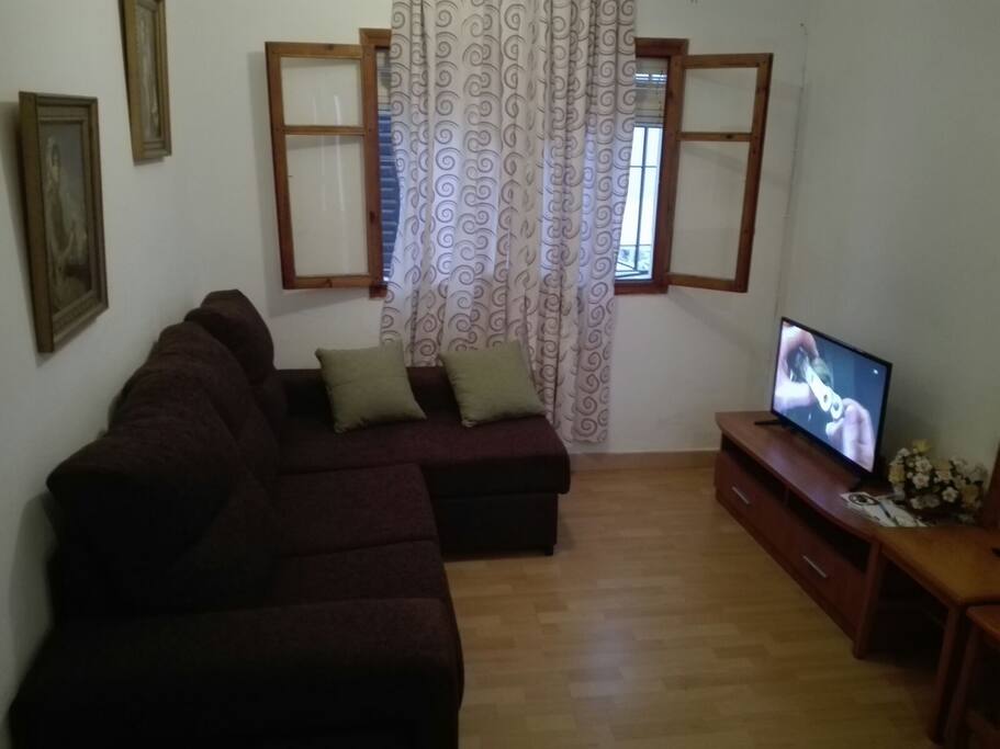 Salón con un cómodo sofá Cheiselonge y TV.