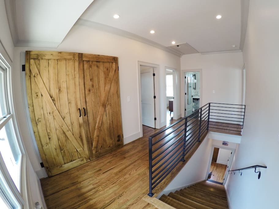 Wide angle of the entrance to the suite. Laundry is located behind barn doors; the bedroom doorways are to the left, and the bathroom is straight down the hallway.