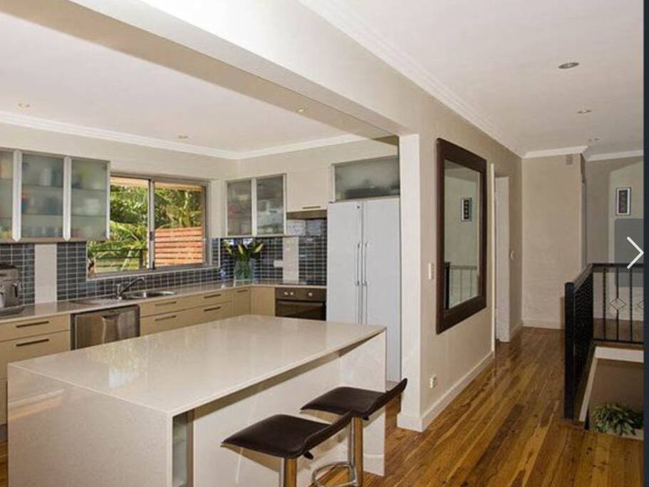 Kitchen and stone breakfast bar with dishwasher and coffee maker.