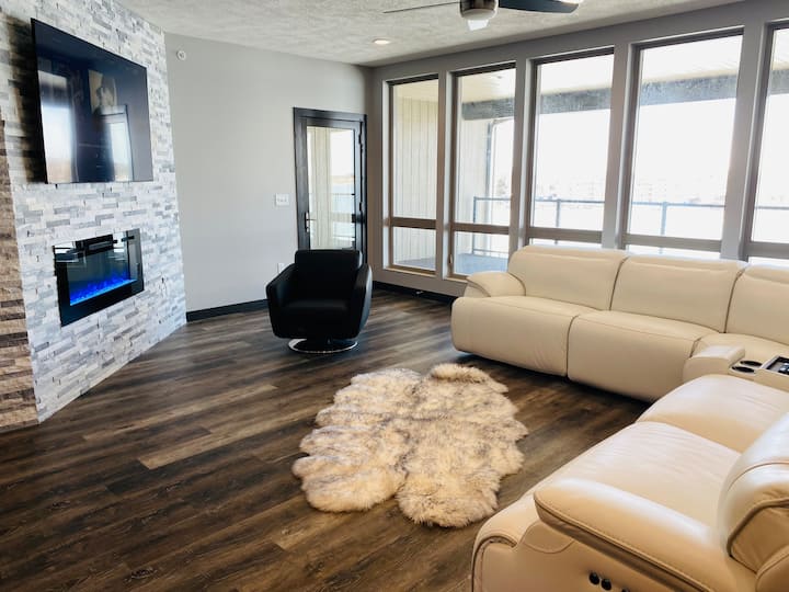 Living room with electric fireplace, flat-screen TV and three sofa recliners to enjoy the direct lakefront view
