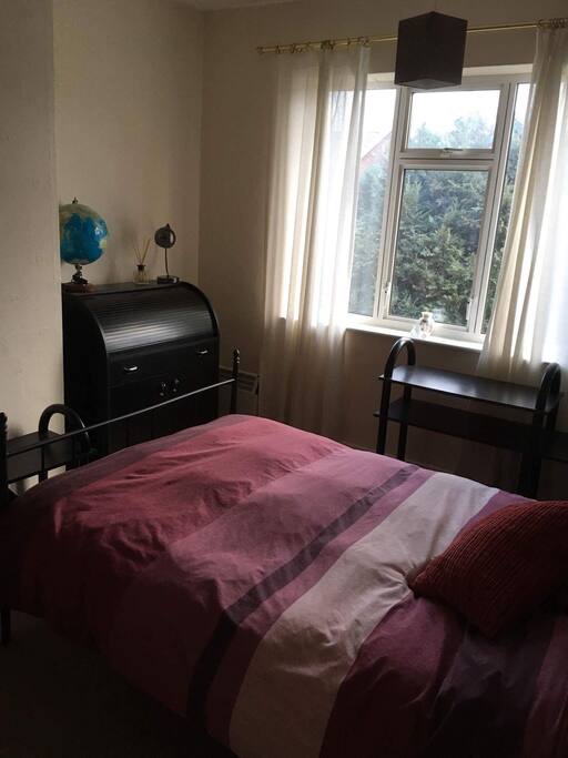 Spacious, furnished bedroom with desk, chair and wardrobe.