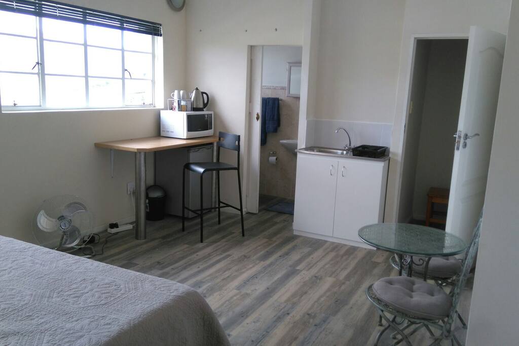 Counter with coffee facilities, fridge and a coffee table. in the back the bathroom