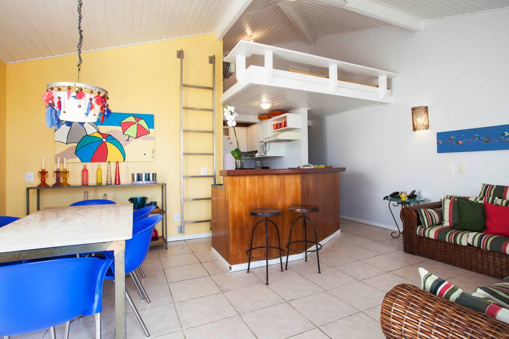 Visão da entrada da sala com cozinha e mezanino