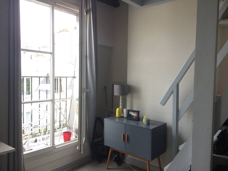 Petit balcon avec table et chaise. Grande fenêtre qui laisse entrer la lumière