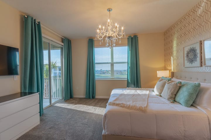 Chambre principale spacieuse et lumineuse avec lit King Size, salle de bains privative, télévision connectée et porte patio donnant sur un balcon privé