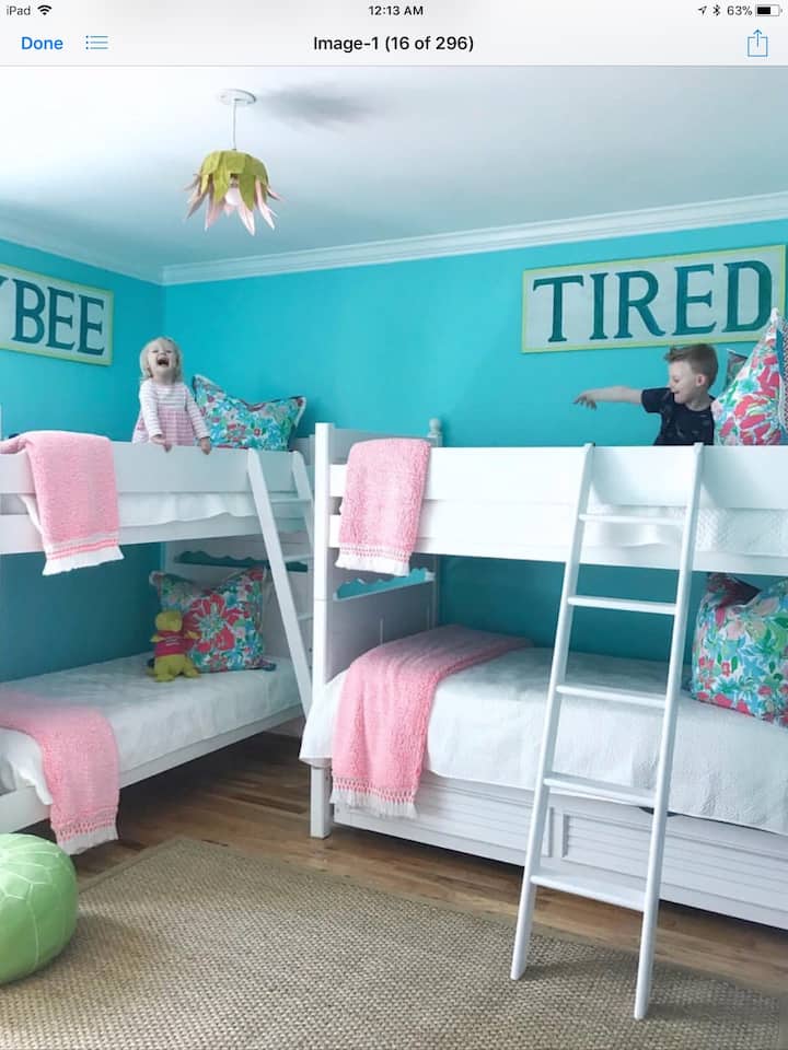 Guest room with two sets of bunk beds, a trundle bed and a flat screen TV.  A bathroom  with two sinks and a private toilet room is connected to this bedroom.