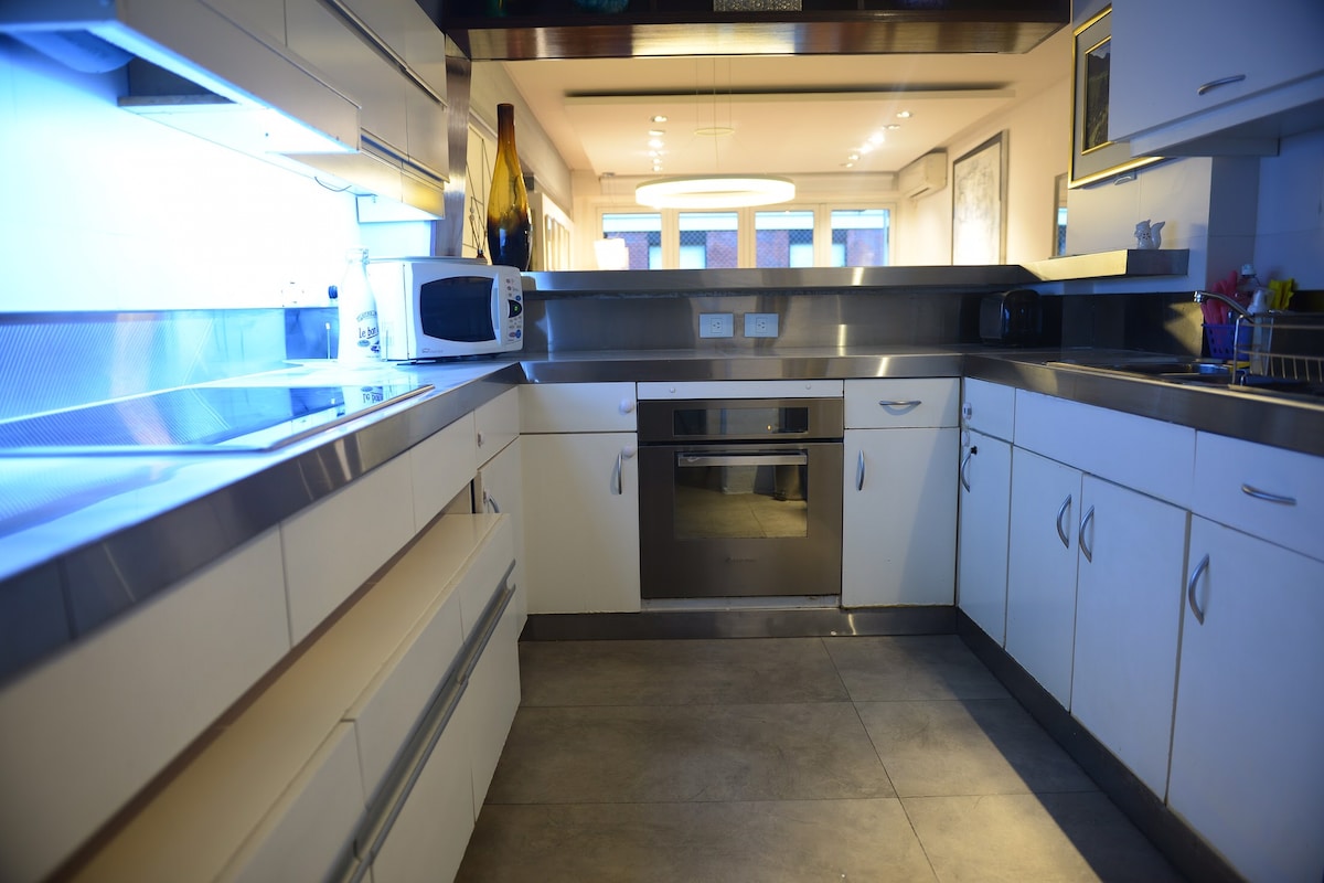 The kitchen features modern, sleek cabinetry with stainless steel finishes. Appliances include a microwave and a built-in dishwasher, enhancing the functionality. Ample counter space is available, along with well-organized storage and lighting that illuminates the area.