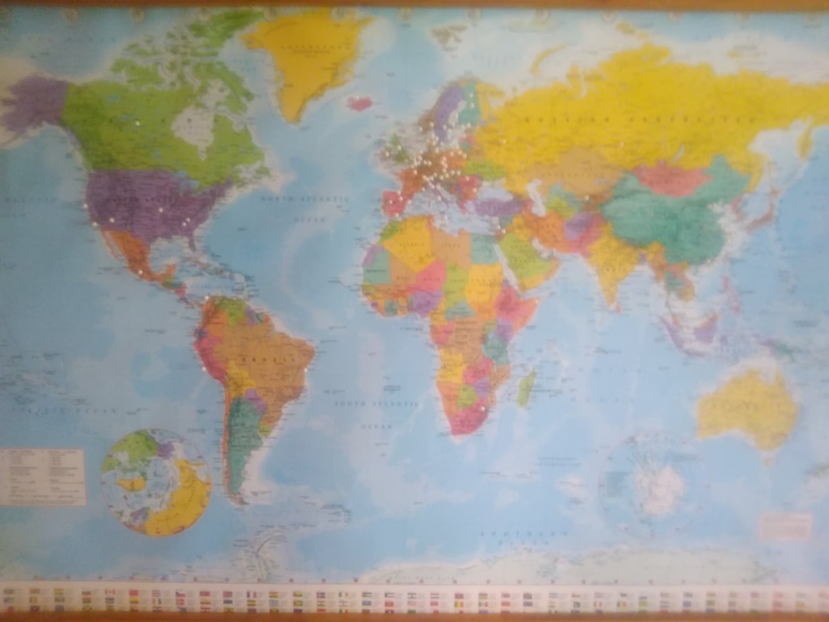 A large world map is displayed on the wall, featuring colorful countries and continents. Major oceans are represented in light blue, while various landmarks are noted with pins. A map legend is located in the lower left corner, providing context for the colors used.
