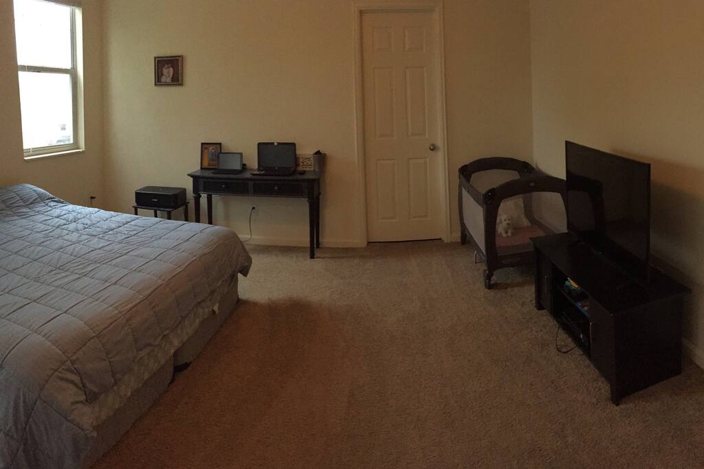 Master bedroom, King bed, pack n' play crib, small desk, and small tv, with on suite bathroom