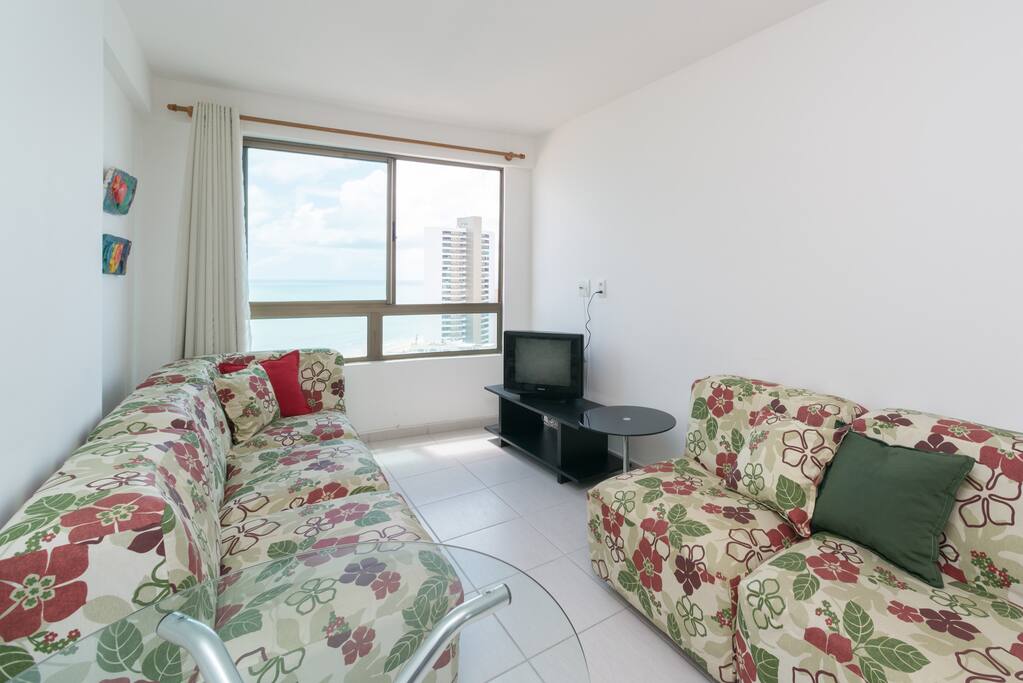 Sala com poltronas, mesa de apoio e televisão