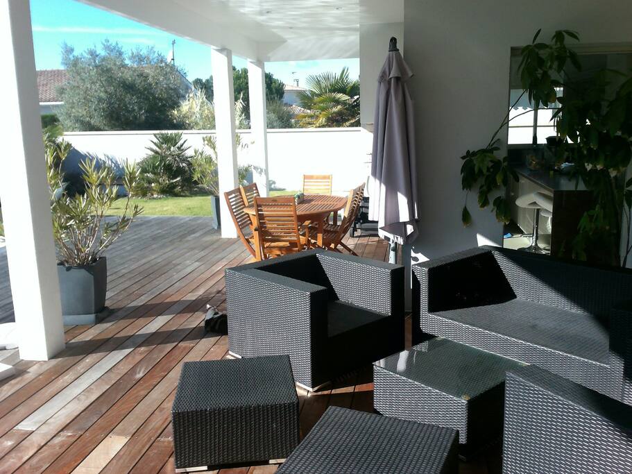 Terrasse couverte avec salon, coin repas avec barbecue et plancha
