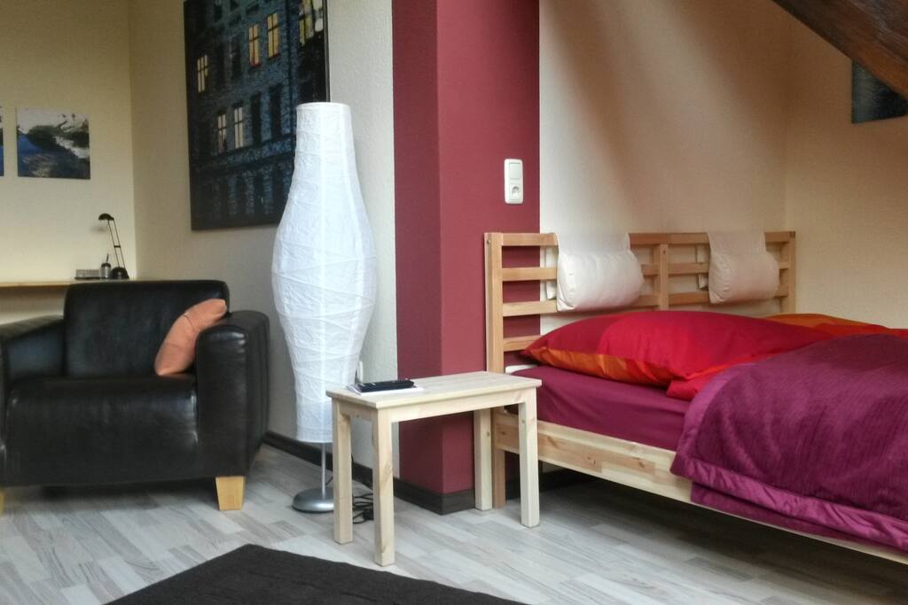 Zimmer 2 mit einem Doppelbett (160cm), Kleiderschrank, Sessel, TV und Schreibtisch.
