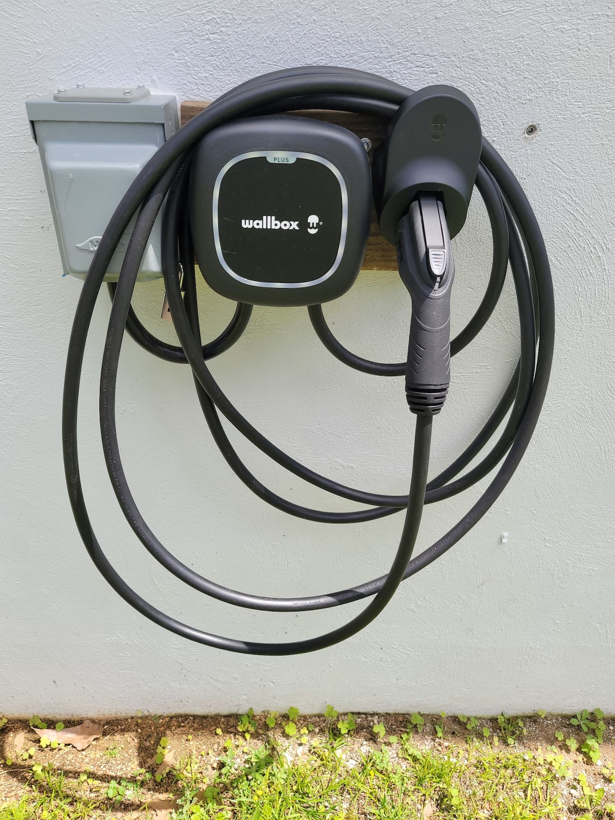 A private Level 2 electric vehicle charger is mounted on the exterior wall, featuring a neatly coiled charging cable. The charger is designed for up to 40 amps, providing convenient access for guests with electric vehicles.