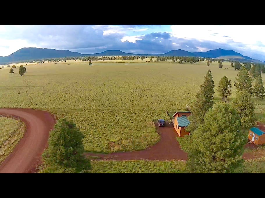 Overhead view of cabin showing the expansive views of surrounding mountains beyond the prairie.