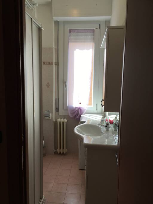Bagno con box doccia, wc, bidet, lavatrice e stendi biancheria a parete.