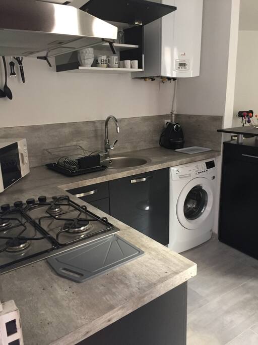 Cuisine neuve équipée machine à laver le linge, micro ondes, four électrique, plaques de cuisson, hotte aspirante, frigo top, Nespresso, vaisselle, ustensiles de cuisine, saladiers, poêles, casseroles.