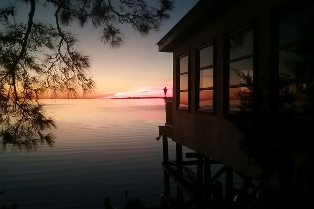 Taken from just beside the bungalow showing your view of the sun setting across the water .