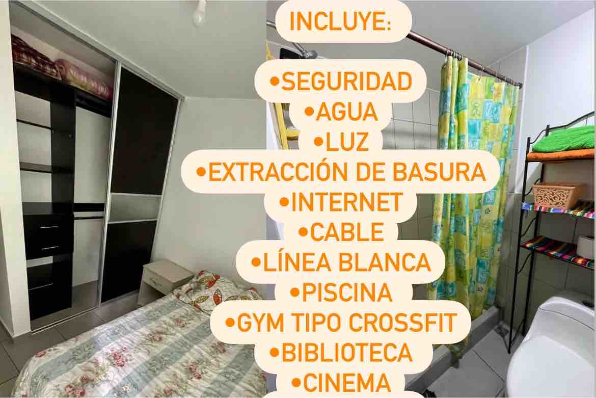 A well-organized room is shown, featuring a comfortable bed with a patterned bedspread. A shared bathroom area is visible, highlighted by colorful shower curtains. Storage options are available with shelves and a wardrobe along the wall. Natural light enters through a window.