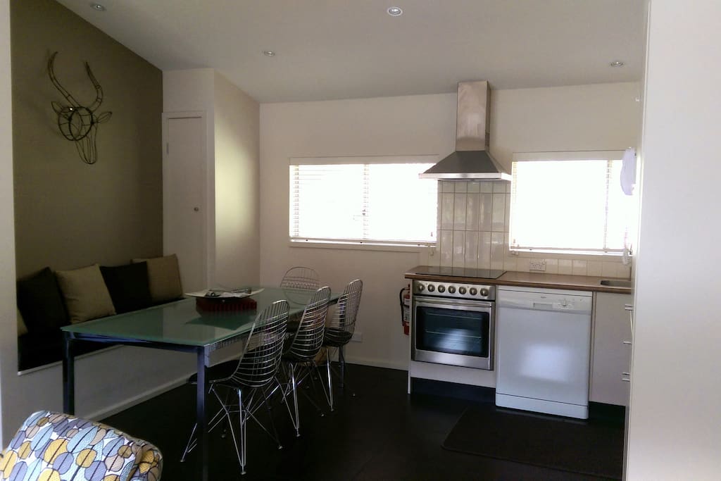 The dining and kitchen look to the rear of the building over the grassy slope. All areas are flooded with natural light