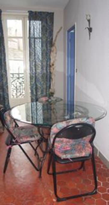 In the living room, a dining area can seat up to six, kitchen behind blue door. Ironwork balcony looks onto church across the street.
