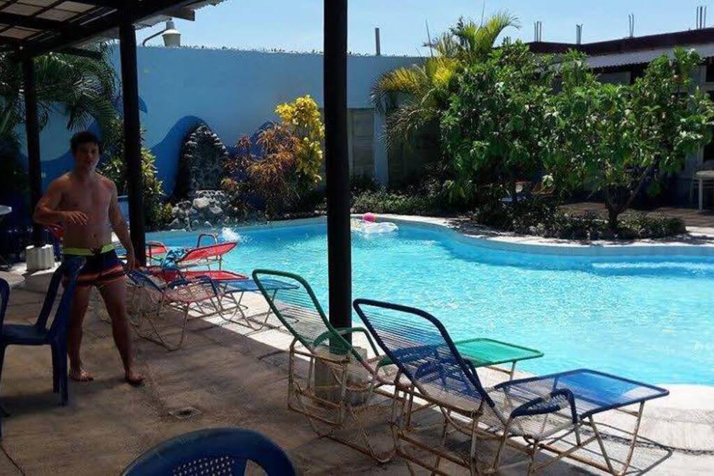 Dos dormilonas para tomar el sol y una mesa con 4 sillas en una pérgona frente a su apartamento.