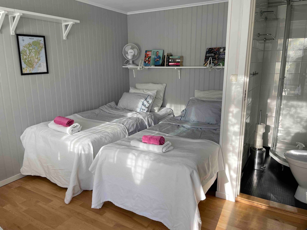 سريران مريحان من قبل الشركة "Hästens". على اليمين يوجد الحمام الصغير الذي يحتوي على دش ومرحاض دافق.