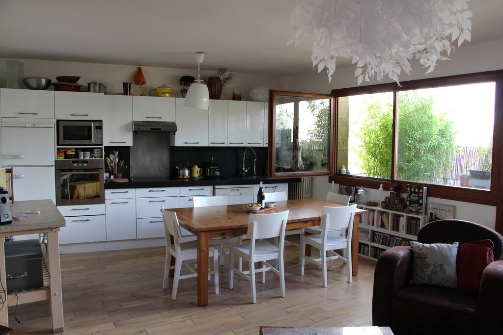 la cuisine américaine la grande table et au fond les bambous sur le balcon