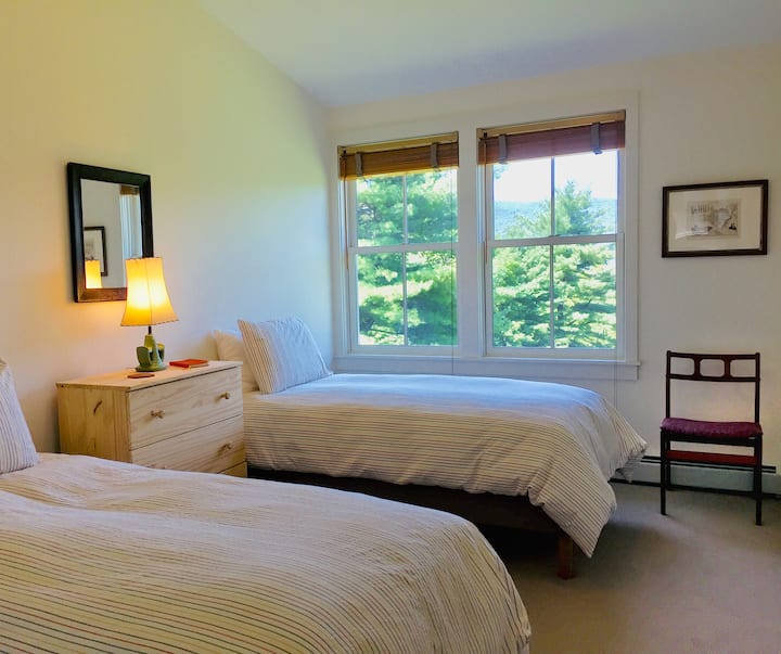 Dormitorio en planta alta con camas individuales y vistas panorámicas a la montaña al norte.