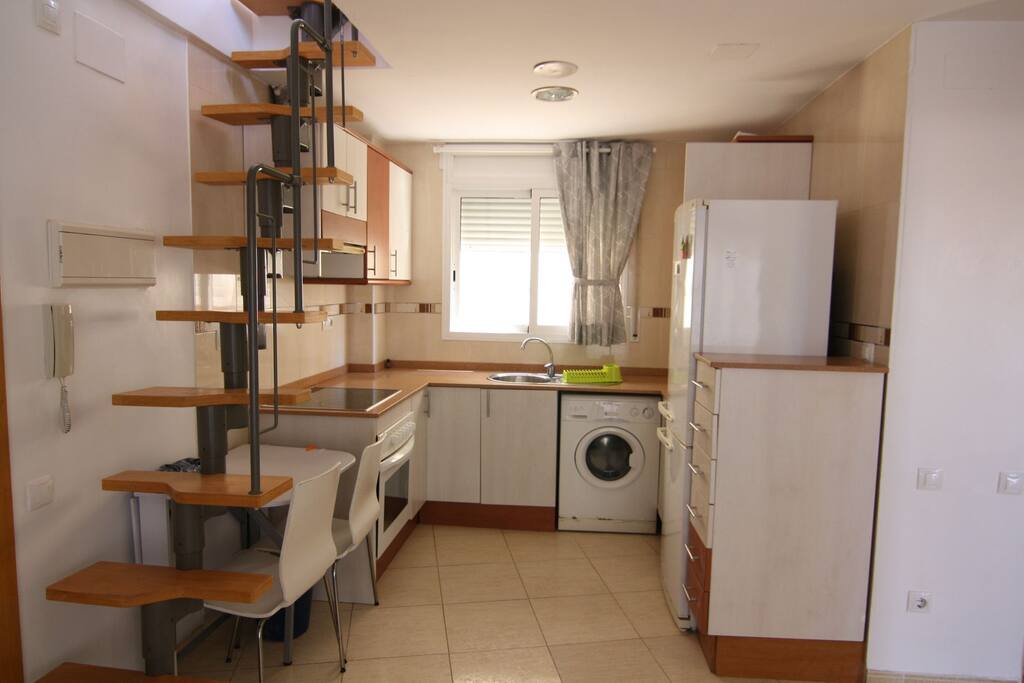 cocina abierta con sillas y mesa plegable para 4 personas.