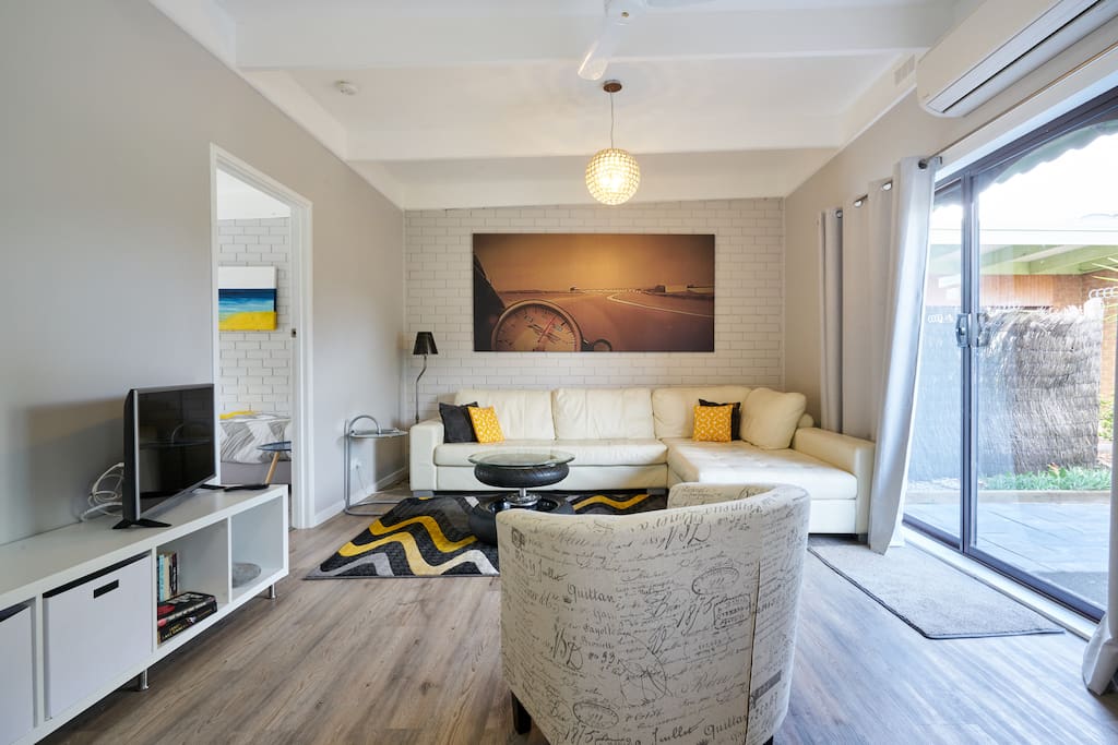 A large open plan lounge room with leather sofa, smart TV with free Netflix and Stan
