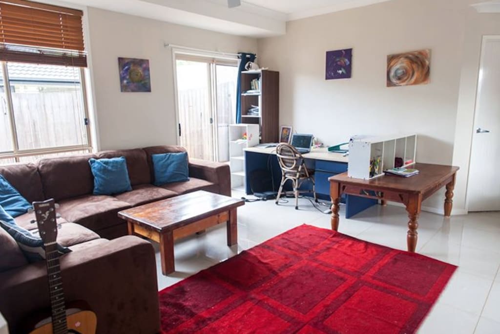 leaving room with a desk and instrument available to play (didgeridoo, guitar, violin, ukulele)