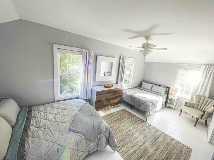 Spavaća soba s dva bračna kreveta i prostorom za sjedenje. 