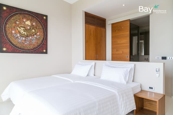 Уютна спалня с бели чаршафи, топли дървени акценти и спокоен дизайн за спокойни нощи.