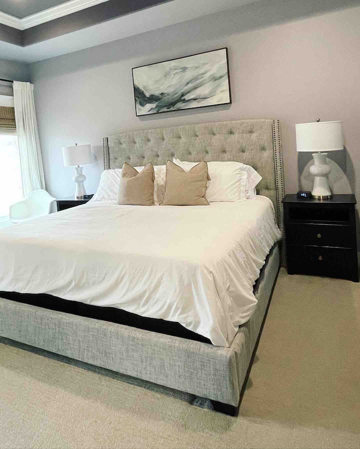 Primaire slaapkamer met een kingsize bed, een bureau met tv die kan worden gebruikt als monitor en verduisteringschermen. 