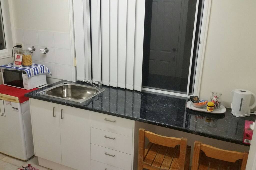 Kitchenette with a fridge, microwave, toaster, kettle, basic cutlery, plates, bowls and cups.