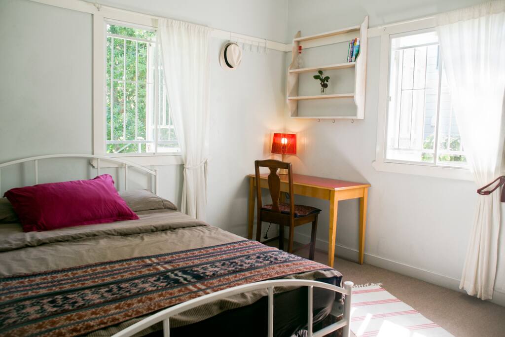 The airy bedroom has a study desk and looks out onto a shady garden.