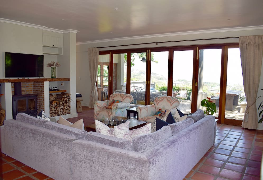 Large lounge, with fireplace, leading onto extensive balcony with stunning sea and mountain views - with braai place and fire pit.