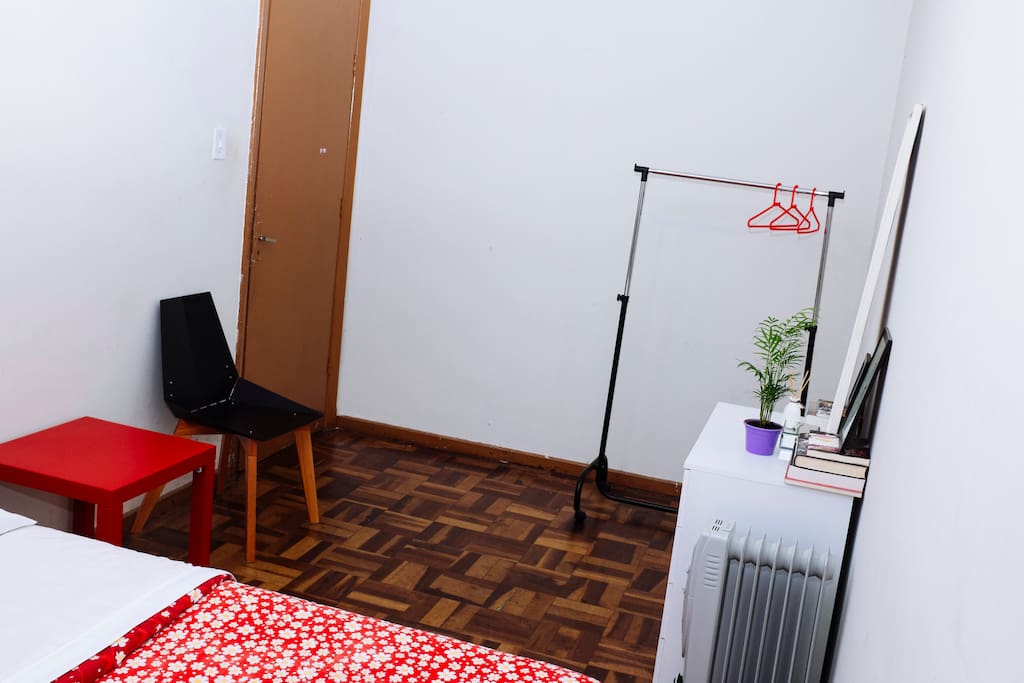 Quarto espaçoso, com arara e cômoda.