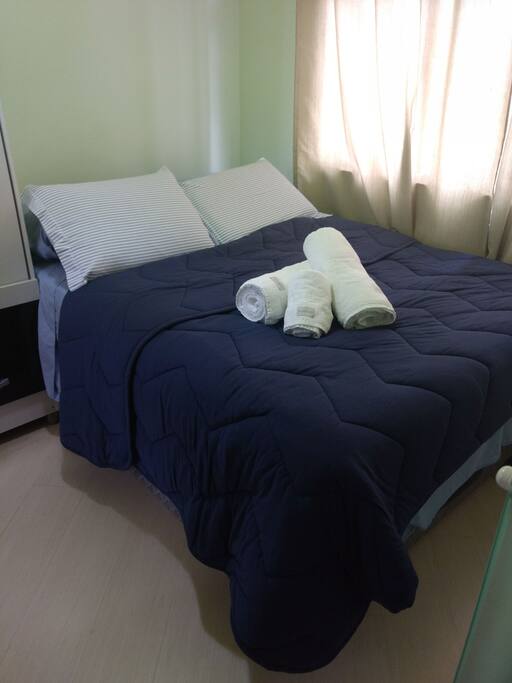 Cama arrumada, roupas de cama e de banho limpas.